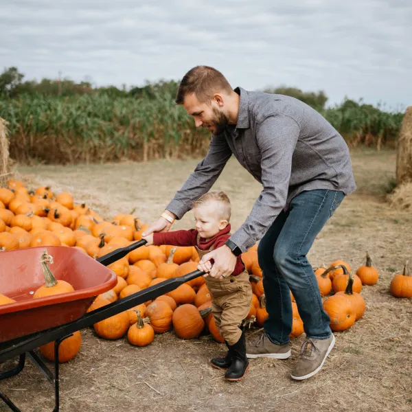 a father works with his child to push a wheelbarrow