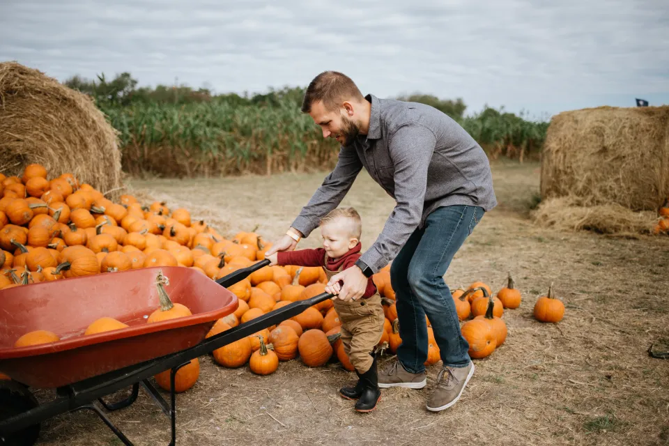 a father works with his child to push a wheelbarrow